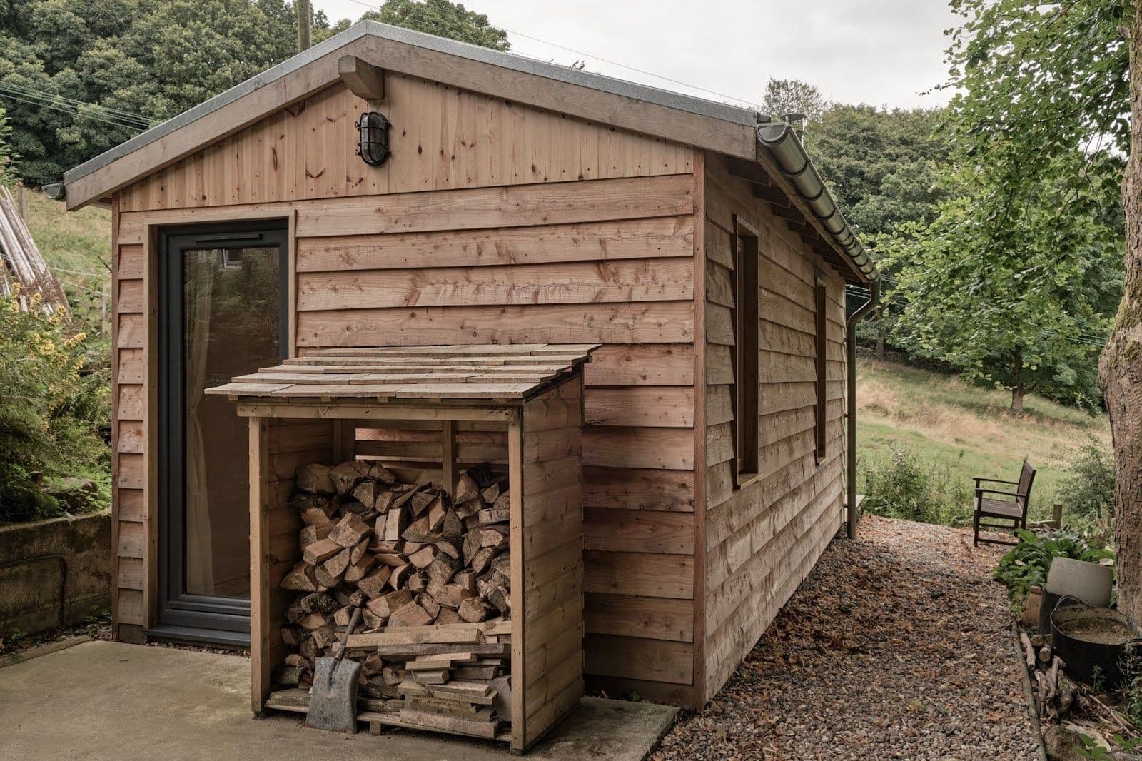 Side view of a wooden clad, beautiful, environmentally friendly cabin with wood storage.